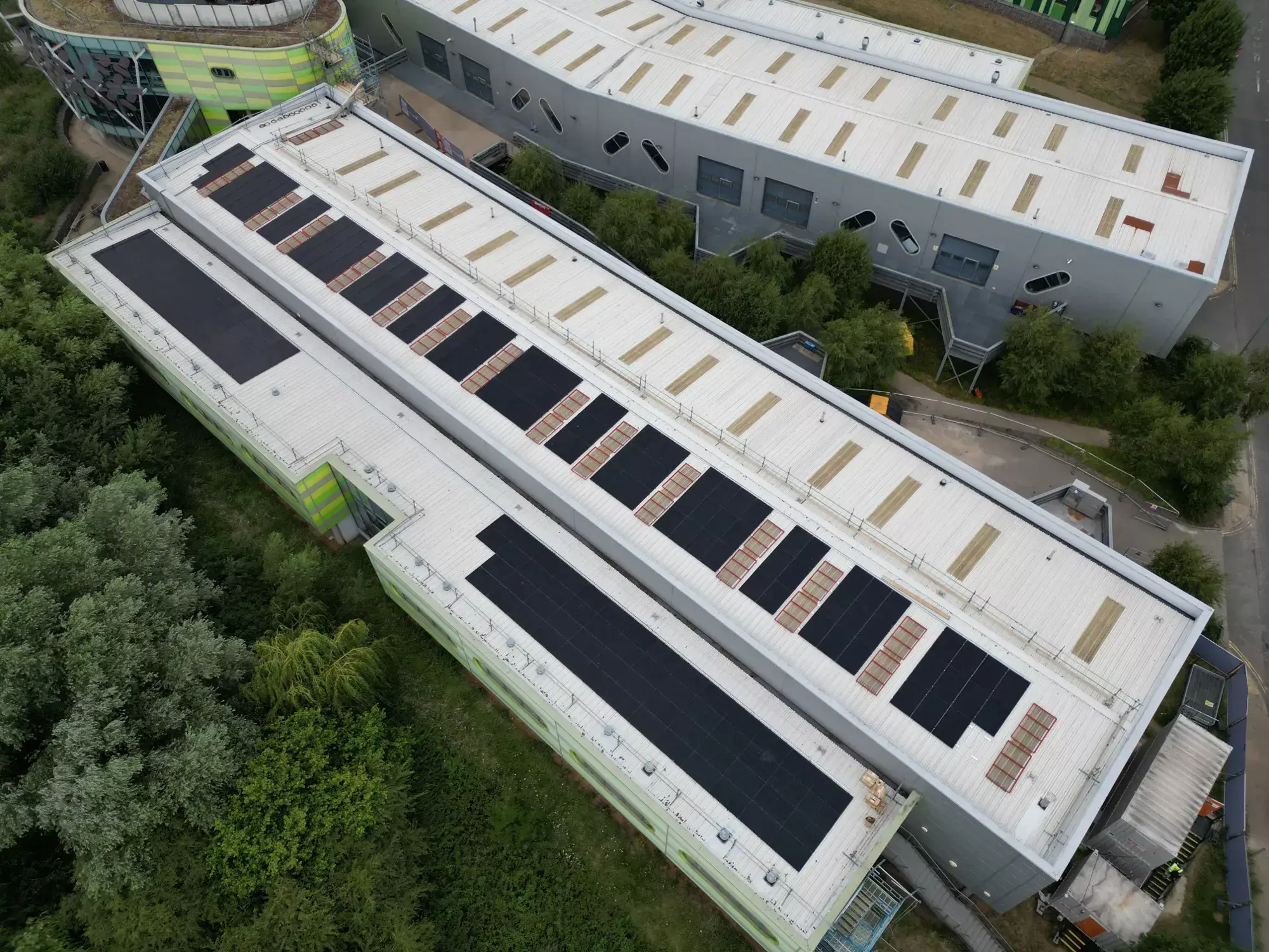 Aerial view of rows of black solar panels on the flat roofs of Nottingham College buildings.